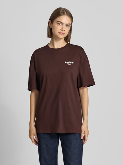 Frauenmodel trägt Oversized Fit T-Shirt aus reiner Baumwolle mit Label-Detail von REVIEW in Dunkelbraun, Ganzkörperansicht von vorne.