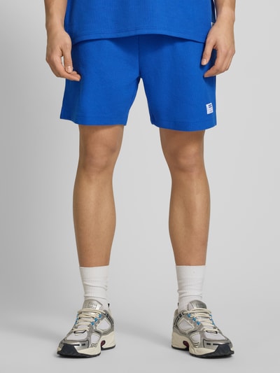 Männermodel trägt Regular Fit Sweatshorts aus Baumwoll-Mix Modell 'NUWAFFLO' von HUGO, Optik: Unifarben, Label-Patch, Ganzkörperansicht von vorne.