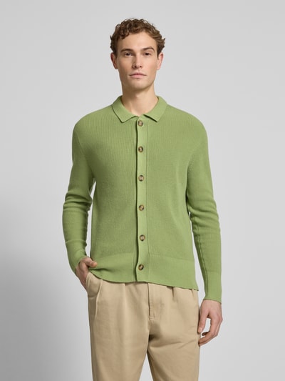 Męski model nosi Regular Fit Strickjacke mit Kaschmir-Anteil od FTC-Cashmere, bawełniany miks z kaszmirem, krój regular fit, zielony, kołnierz wykładany, zapięcie na guziki, elastyczne wykończenia, długość tyłu 71 cm, długość rękawa 68 cm, widok całej sylwetki z przodu.
