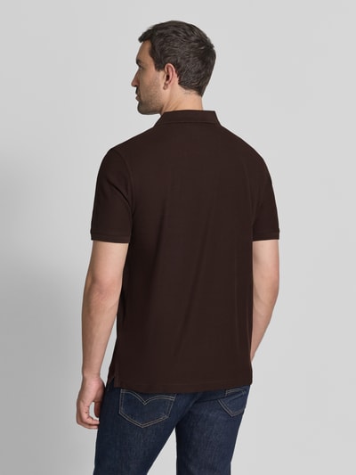 Männermodel trägt dunkelbraunes Regular Fit Poloshirt mit Label-Stitching von Fynch-Hatton aus reiner Baumwolle, Ganzkörperansicht Rückansicht.
