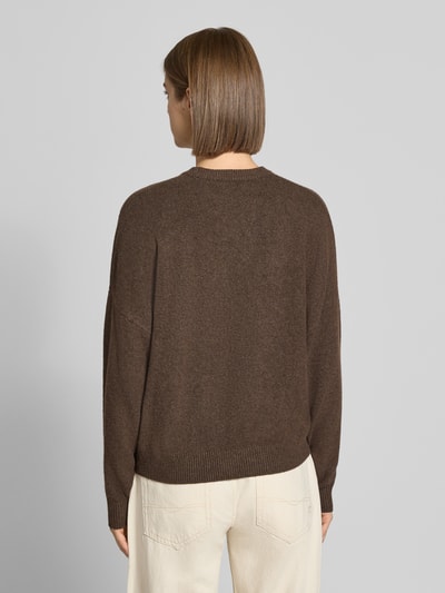 Frauenmodel trägt Strickpullover mit Label-Print von REVIEW in Braun mit lockerem Schnitt und geripptem Saum, Ganzkörperansicht Rückansicht.