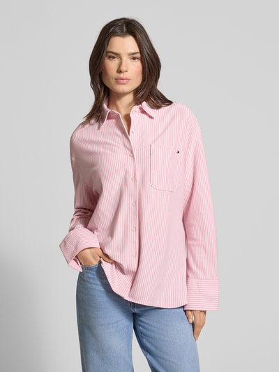 Frauenmodel trägt Oversized Langarmbluse aus Baumwoll-Mix von Tommy Hilfiger in Rosa mit feinen Streifen, Hemdkragen, Brusttasche, Webware, Ganzkörperansicht von vorne.