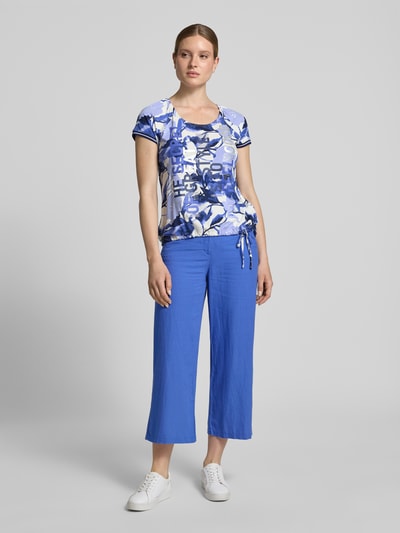 Frauenmodel trägt Damen T-Shirt aus Viskose-Mix mit Kordelzug am Saum von Betty Barclay, Blau, Statement-Print, Strasssteinbesatz, Regular-Fit, Rundhalsausschnitt, Rückenlänge bei Größe 36: 60 cm, Ganzkörperansicht von vorne.
