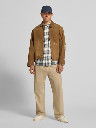Männermodel trägt Slim Fit Freizeithemd aus reiner Baumwolle Modell 'James' von JACK & JONES in Karomuster, Ganzkörperansicht von vorne.