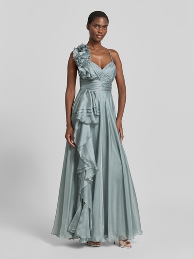 Modelka nosi 'Abendkleid mit Volants und Herz-Ausschnitt' od V.M., satyna, A-linia, maxi, dekolt serce, ramiączka krzyżowane z tyłu, wolanty, tylny zamek i haftka; długość pleców w rozmiarze 36: 122 cm, szerokość w rozmiarze 36: 32 cm, srebrzysty kolor, gładka tekstura. Widok całej sylwetki z przodu.