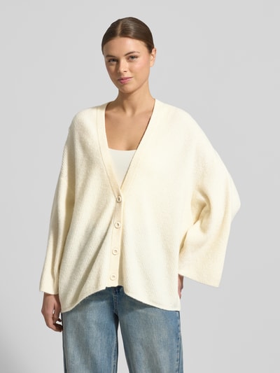 Frauenmodel trägt Relaxed Fit Cardigan mit Woll-Anteil Modell 'Damsville' von American Vintage in Creme mit V-Ausschnitt und Knopfleiste, Strick-Optik, elastischer Material-Mix, Ganzkörperansicht von vorne.