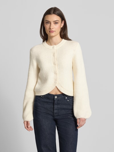 Frauenmodel trägt Strickjacke mit Rundhalsausschnitt Modell 'Ally' von Gina Tricot, cremefarben, Regular Fit, Knopfleiste, Ganzkörperansicht von vorne.