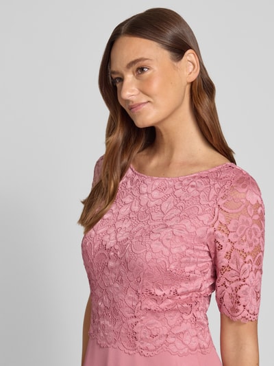 Kobiece modelka ma na sobie Knielanges Cocktailkleid mit Spitze und Rundhalsausschnitt od Vera Mont, szyfon, linia A, długość do kolan, koronka, okrągły dekolt, długość tyłu w rozmiarze 36: 105 cm, szerokość w rozmiarze 36: 40 cm, długość rękawów w rozmiarze 36: 28 cm, różowe odcienie, kwiatowa faktura koronki, zbliżenie górnej części ciała, z przodu.