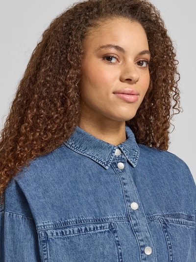 Modelka nosi Oversized Hemdbluse in Denim-Optik Model 'Enza' von Noisy May, czysta bawełna, krój oversized fit, tkanina stylizowana na denim, długi rękaw, kołnierzyk koszulowy, kieszenie na piersi, listwa z zatrzaskami, długość tyłu w rozmiarze S: 62 cm, długość rękawów w rozmiarze S: 52 cm, zbliżenie na górną część ciała.