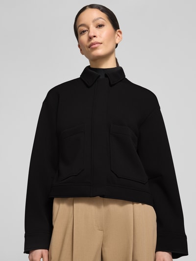 Frauenmodel trägt Jacke mit Umlegekragen Modell 'Jenima' von OPUS, schwarz, Material-Mix mit Viskose, Nahaufnahme Oberkörper.