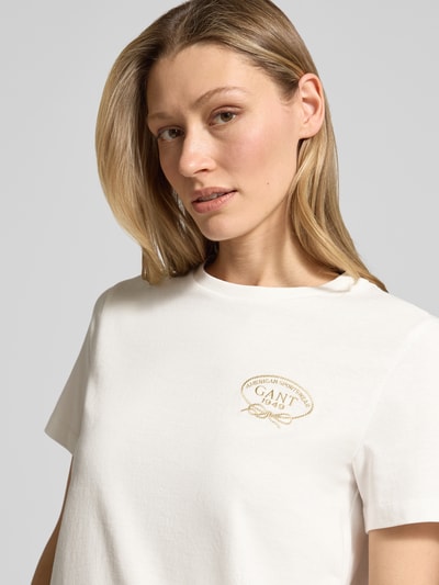 Vrouwenmodel draagt T-shirt met ronde hals en logoprint van Gant, puur katoen, regular fit, ruglengte bij maat S 56 cm, close-up bovenlichaam.