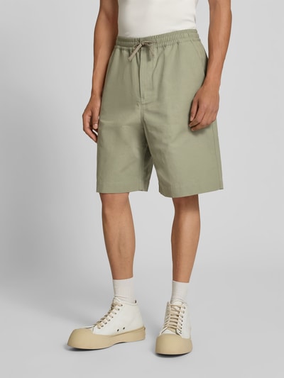 Männermodel trägt Shorts aus Baumwoll-Mix von MAISON KITSUNÉ in Grün, Regular-Fit, elastischer Bund, Eingrifftaschen, Knielänge, Ganzkörperansicht von vorne.