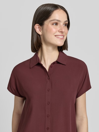 Frauenmodel trägt Relaxed Fit Bluse aus Viskose von Christian Berg Woman in dunklem Rot mit Hemdblusenkragen, Knopfleiste, Kappärmel, Nahaufnahme Oberkörper. Rückenlänge bei Größe 36: 63 cm, Ärmellänge bei Größe 36: 17 cm.