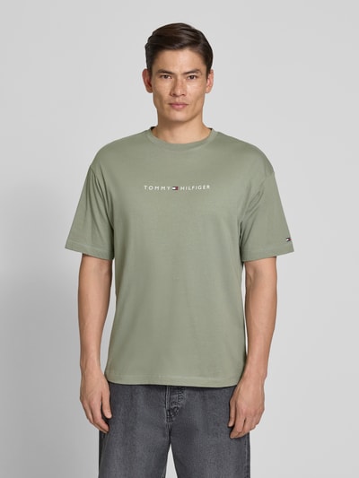 Männermodel trägt Regular Fit T-Shirt mit Label-Schriftzug aus reiner Baumwolle von Tommy Hilfiger in Optik: Unifarben, Ganzkörperansicht von vorne.