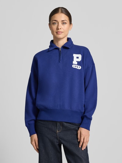 Frauenmodel trägt Loose Fit Sweatshirt aus Baumwoll-Mix von Polo Ralph Lauren in Blau mit weißem Logo, glatte Textur, Ganzkörperansicht von vorne. Damen Sweatshirt von Polo Ralph Lauren