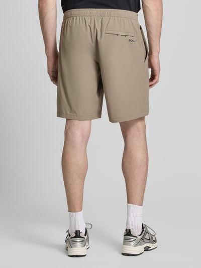 Männermodel trägt Regular Fit Sport-Shorts mit Label-Print Modell 'TREVOL' von BOSS Green in Beige, Materialverarbeitung: 4-Wege-Stretch, elastischer Bundabschluss, seitliche Eingrifftaschen, Gesäßtasche, Ganzkörperansicht Rückansicht.