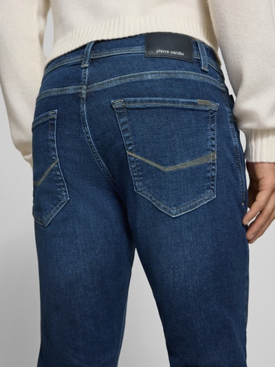 Männermodel trägt Regular Fit Jeans im 5-Pocket-Design Modell 'Lyon' von Pierre Cardin in Dunkelblau, Detailaufnahme Rückansicht, elastischer Baumwoll-Mix mit Lyocell-Anteil, sichtbares Label am Bund, Kontext: Herren Jeans, Knopf- und Reißverschluss, Bundweite 41 cm, Innenbeinlänge 79 cm.