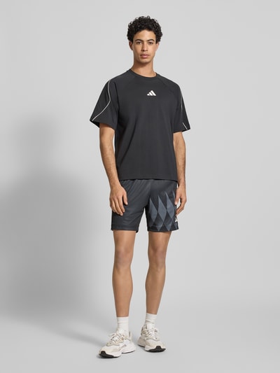 Männermodel trägt Regular Fit Shorts mit Logo-Print Modell 'Tiro' von adidas Sportswear, elastischer Bund, dunkle Farbe, Ganzkörperansicht von vorne.