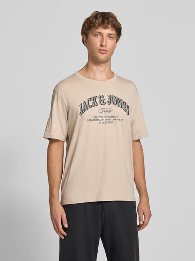 Männermodel trägt Regular Fit T-Shirt aus reiner Baumwolle Modell 'Denver' von JACK & JONES in Beige mit Logo-Print, Nahaufnahme Oberkörper. Herren T-Shirt, Rückenlänge bei Größe M 69 cm.