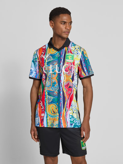 Männermodel trägt Regular Fit T-Shirt mit V-Ausschnitt von COLUCCI, bunt gemustert mit Umlegekragen und Logo-Stitching, Ganzkörperansicht von vorne.
