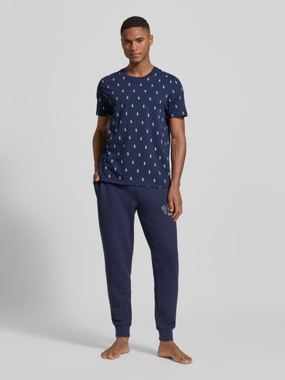 Männermodel trägt Regular Fit Pyjama-Oberteil aus reiner Baumwolle Modell 'CREW-SLEEP-TOP' von Polo Ralph Lauren Underwear, Dunkelblau mit Polo-Pony-Muster, Crew Neck, kurzarm, Ganzkörperansicht von vorne