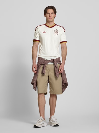 Männermodel trägt Spanien Auswärtstrikot 2026 von adidas Sportswear, meerkleurig, regular fit, clublogo, contraststrepen, logo-stiksel, ronde hals, korte mouw, CLIMACOOL-technologie, volledig lichaam vooraanzicht.