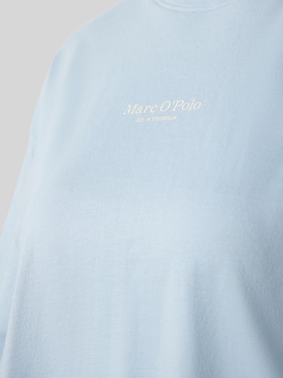 Kobiece modelka nosi Boxy Fit Pyjama-Oberteil aus reiner Baumwolle od Marc O'Polo, efekt: jednolity kolor, pudełkowy krój, nadruk z logo, okrągły dekolt, krótki rękaw, czysta bawełna, z wycięciami po bokach, widok zbliżeniowy na górną część ciała.