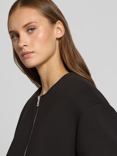 Kobiece modelka nosi czarną bluzę rozpinaną Regular Fit Sweatjack z dodatkiem wiskozy model 'LELLIE' od ONLY, damska bluza rozpinana, zbliżenie na górną część ciała.