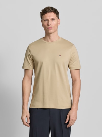 Männermodel trägt Regular Fit T-Shirt aus reiner Baumwolle von Tommy Hilfiger in uni beige, kurzarm, Rundhals, met logo-detail, ganzkörperansicht von vorne.