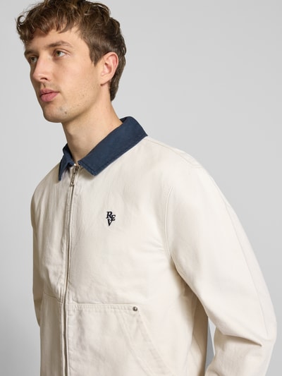 Männermodel trägt Regular Fit Übergangsjacke in denimlook van REVIEW aus puur katoen, platte kraag, ritssluiting, kangoeroezak, nahaufnahme oberkörper.