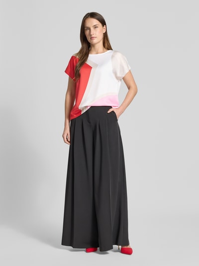 Frauenmodel trägt Regular Fit T-Shirt mit Allover-Muster von s.Oliver BLACK LABEL, abstrakter Druck in Rot, Rosa und Weiß, Rundhals, Kurzarm, Materialmix aus Satin und Jersey, Viskose-Mix, Ganzkörperansicht von vorne.