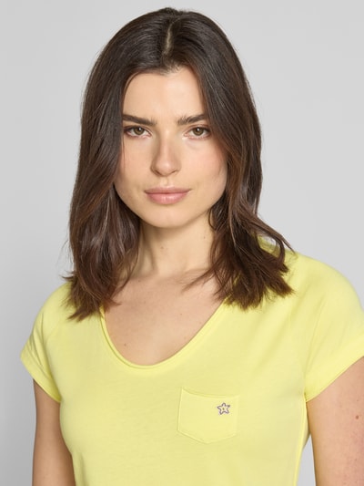 Kobiece model prezentuje damski t-shirt z bawełny, krój regular fit, dekolt w serek, brustasza, G.I.G.A. DX, model 'GS23', długość tyłu 64 cm w rozmiarze 36, jasny żółty kolor, widoczne gładkie tekstury, zbliżenie na górną część ciała
