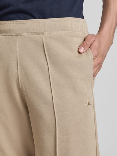 Männermodel trägt Bermudas mit elastischem Bund und Label-Stitching von CHAMPION in Beige, Baumwoll-Mix, Nahaufnahme Hüfte.