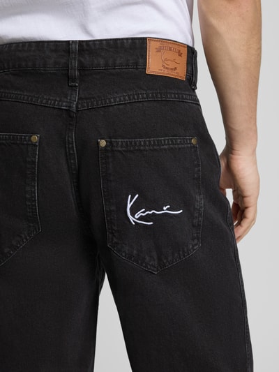 Männermodel trägt Baggy Jeans im 5-Pocket-Design mit Logo-Stitching von KARL KANI, schwarze Baumwolle, Detailaufnahme Rückansicht.
