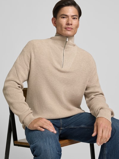 Męski model nosi Regular Fit Troyer aus Viskose-Mix von Jake*s Studio Men, beżowy sweter o żebrowanej fakturze, zamek pod szyją, tekstura miękka, jeansy, zdjęcie w półzbliżeniu, widok z przodu.