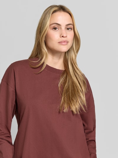 Vrouwenmodel draagt Relaxed Fit Langarmshirt aus Baumwolle van American Vintage in bruin, katoen, ronde hals, trendy, met lange mouwen, bies, ruglengte maat XS/S: 64 cm, nahaufnahme bovenlichaam.