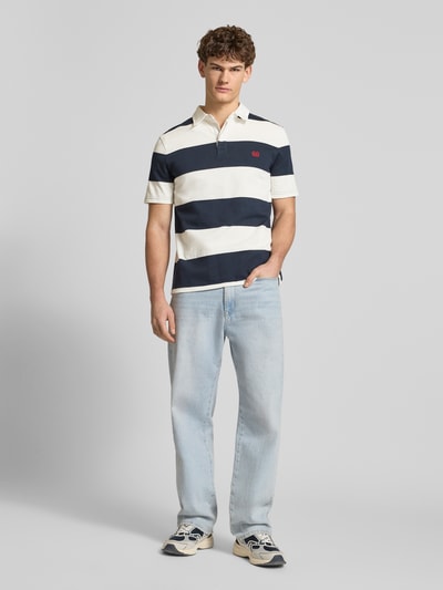 Männermodel trägt Regular Fit Poloshirt mit Rugby-Streifen und Logo-Bestickung von REVIEW aus Reine Baumwolle, Ganzkörperansicht von vorne.