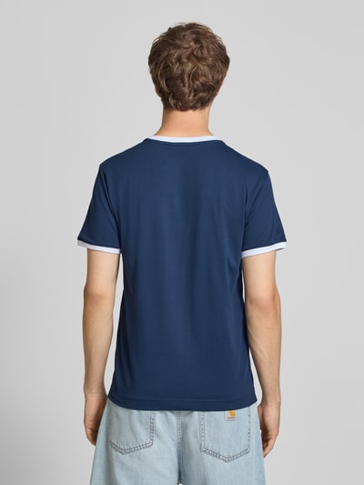 Mannenmodel draagt t-shirt in donkerblauw met witte accenten, Model 'RINGETTO' van ellesse, puur katoen, regular fit, retrolook, labelstitchings, ronde hals, ruglengte bij maat M 70 cm, Ganzkörperansicht Rückansicht.