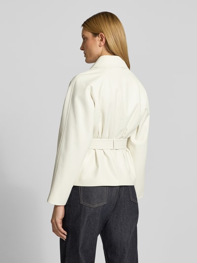Modelka kobieca nosi Regular Fit Kunstlederjacke mit Bindegürtel Modell 'AISANDI' od HUGO, gładka tekstura, kolor biały, krój regular fit, długo rękaw, pasek, widok całej sylwetki z tyłu.