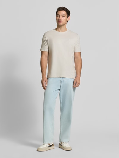 Männermodel trägt Regular Fit T-Shirt aus reiner Baumwolle mit Logo-Print von Marc O'Polo in Beige und Jeans, Ganzkörperansicht von vorne. Herren T-Shirt von Marc O'Polo.