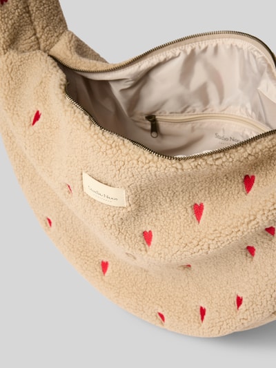 Produktfoto, Shoulder Bag aus Teddyfell mit Logo-Detail von Studio Noos, beige mit roten Herz-Stitchings, Reißverschluss, weiche Textur, kontrastierendes Innenfutter, Hauptfach, Schulterriemen, Allover-Muster, Maße und Details gemäß Kontext.