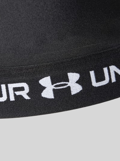 Produktfoto, schwarzer Sport-BH mit Logo-Print von Under Armour, glatte Oberfläche, weißer Schriftzug und Under Armour Logo, Detailaufnahme.