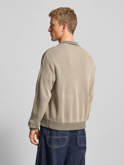Männermodel draagt Strickjacke mit Umlegekragen und Label-Stitching van Pegador in beige, puur katoen, regular fit, ruglengte 70 cm, mouwlengte 68 cm, platte kraag, ritssluiting, labelstitching, Ganzkörperansicht Rückansicht.