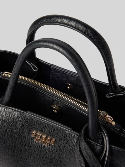Produktfoto, Handtasche in Leder-Optik Modell 'Amorette' von GUESS in Schwarz mit geteiltem Hauptfach, Magnetverschluss, Logo-Detail, Nahaufnahme
