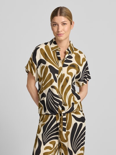 Frauenmodel trägt Regular Fit Bluse aus Viskose mit Knotendetail Modell 'FELDI' von Soyaconcept, Allover-Muster in Beige, Schwarz, Braun, Hemdblusenkragen, verdeckte Knopfleiste, Nahaufnahme Oberkörper.