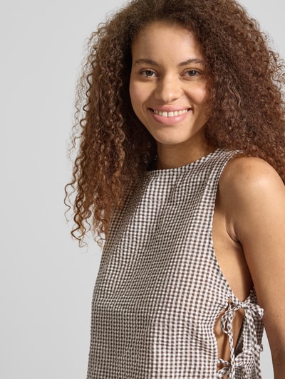 Kobiece modelka nosi Blusentop mit seitlicher Schnürung Modell 'ELIZA' von Noisy May, mieszanka bawełny, krój regular fit, okrągły dekolt, wiązanie z boku, długość tyłu w rozmiarze S: 50 cm, wzór w kratę, jasnobrązowo-biała kolorystyka, tekstura gładka, zbliżenie na górną część ciała