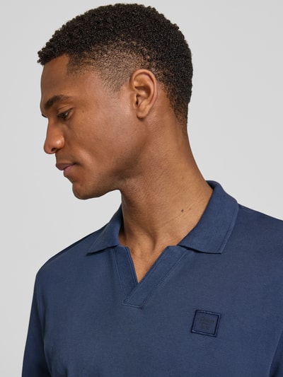 Männermodel trägt Regular Fit Poloshirt aus reiner Baumwolle von s.Oliver RED LABEL, Optik: Unifarben, Label-Patch, Nahaufnahme Oberkörper.