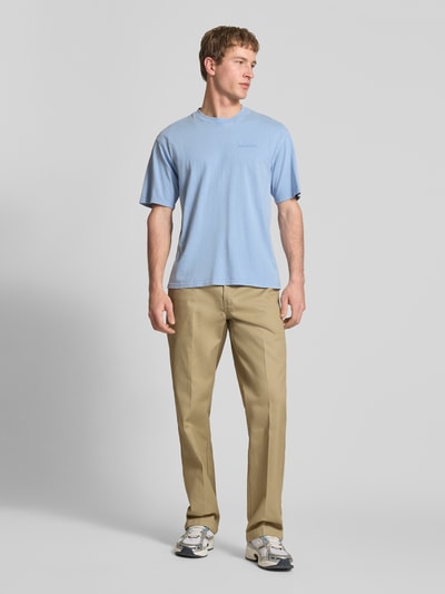 Männermodel trägt T-Shirt mit Rundhalsausschnitt und Label-Stitching von Dickies, hellblau, Regular Fit, reine Baumwolle, Ganzkörperansicht von vorne.