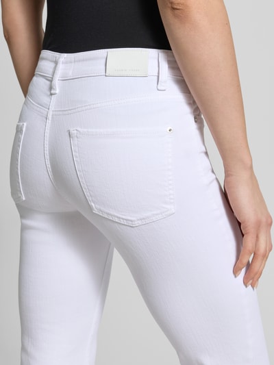 Kobiece model nosi Flared Jeans im 5-Pocket-Design Modell 'PARIS' von Cambio, mieszanka bawełny z dodatkiem streczu, rozkloszowany krój, 5 kieszeni, zapięcie na guzik i zamek błyskawiczny, szerokość w rozmiarze 36: 36 cm, długość wewnętrzna nogawki w rozmiarze 36: 81 cm, białe, faktura gładka, widok całej sylwetki z tyłu