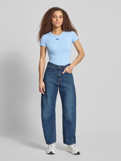 Frauenmodel trägt Slim Fit T-Shirt aus Baumwoll-Mix Modell 'EASY TEE' von HUGO BLUE, jednokolorowy, naszywka z logo, okrągły dekolt, krótki rękaw, prążkowana faktura, damski t-shirt, Ganzkörperansicht von vorne.